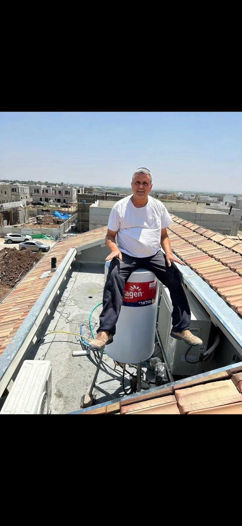 בצלאל בוכריס לצד מערכת דוד שמש על גג
